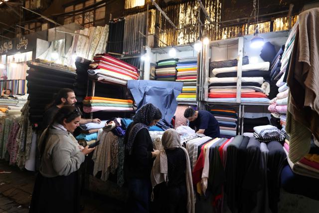 Women shop for cloth at a store in the Grand Bazaar in Tehran on August 1, 2026. Iran's military accused the United States of "escalating tensions" in the Middle East on August 1, and warned countries in the region against cooperating with Washington during the ongoing conflict. (Photo by ATTA KENARE / AFP) / 