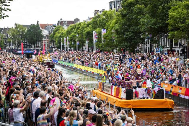 Participants on boats pass next to spectators on a canal as they take part in the Canal Parade of the Pride celebrations in Amsterdam on August 1, 2026. (Photo by Remko de Waal / ANP / AFP) / Netherlands OUT