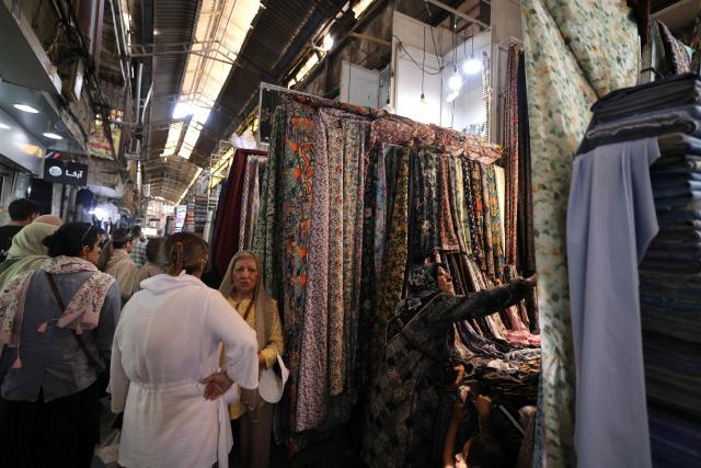 Women shop for cloth at a store in the Grand Bazaar in Tehran on August 1, 2026. Iran's military accused the United States of "escalating tensions" in the Middle East on August 1, and warned countries in the region against cooperating with Washington during the ongoing conflict. (Photo by ATTA KENARE / AFP) / 