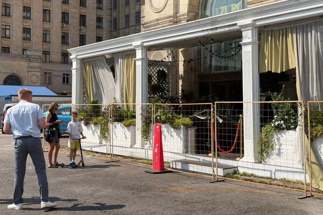 People stand next to the fenced terrace of a restaurant in Moscow on August 2, 2026, the day after a blast. An explosion on August 1, 2026 at a Moscow restaurant that killed three people and wounded 21 others was a bombing, Russia's national anti-terrorism committee said, according to the Tass state news agency. (Photo by Tatyana MAKEYEVA / AFP)