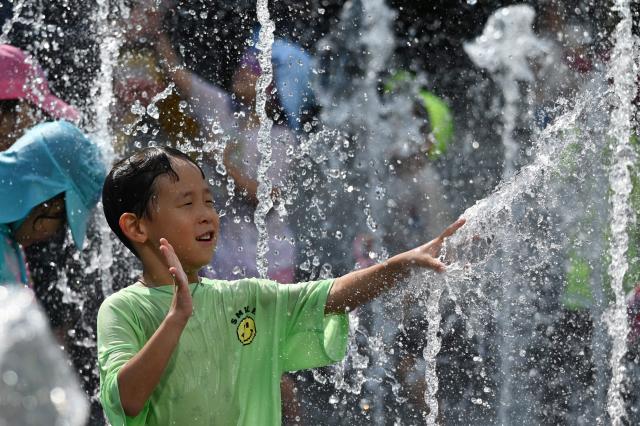 A boy plays in a fountain to cool off in Seoul on August 2, 2026. South Korea registered its highest temperature since records began more than a century ago on August 2, as authorities warned people to "immediately" stop all outdoor activities in affected areas. (Photo by GREG BAKER / AFP)