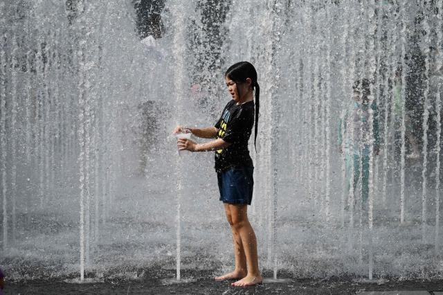 A girl plays in a fountain to cool off in Seoul on August 2, 2026. South Korea registered its highest temperature since records began more than a century ago on August 2, as authorities warned people to "immediately" stop all outdoor activities in affected areas. (Photo by GREG BAKER / AFP)