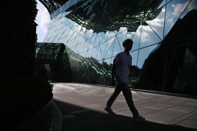 A man walks between buildings in Seoul on August 2, 2026. South Korea registered its highest temperature since records began more than a century ago on August 2, as authorities warned people to "immediately" stop all outdoor activities in affected areas. (Photo by GREG BAKER / AFP)