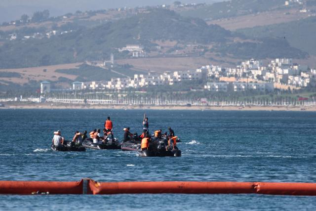 People aboard inflatable boats navigate on the Moroccan side of the new floating barrier deployed by Spain to reinforce security near the border post of the Spanish enclave of Ceuta on August 2, 2026. At least 72 people died during last week's mass influx of migrants into Spain's Ceuta enclave, when tens of thousands of people mostly swam around the border post from Morocco, local officials said today. Most of the estimated 60,000 people who rushed into Spain's north African territory have returned to Morocco since the territory's largest mass migrant crossing. (Photo by Henry Nicholls / AFP)