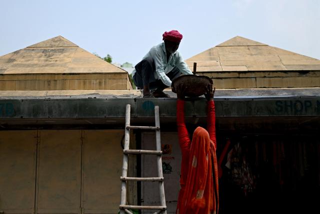 Labourers work on the roof of a shop in New Delhi on August 2, 2026. (Photo by Sajjad HUSSAIN / AFP)