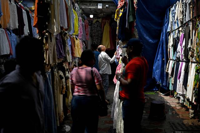 A vendor arranges clothes displayed at his shop in a marketplace in New Delhi on August 2, 2026. (Photo by Sajjad HUSSAIN / AFP)