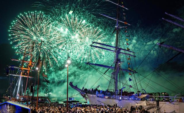 Spectators watch the closing fireworks for The Tall Ships Races 2026 as they illuminate the night sky over the Norwegian training ship Statsraad Lehmkuhl (R) at the port of Aalborg, Denmark on August 1, 2026. 51 sailing ships visit the Aalborg and Noerresundby waterfronts from July 30 - August 2, 2026. (Photo by Henning Bagger / Ritzau Scanpix / AFP) / Denmark OUT