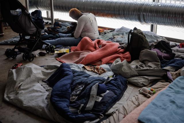 A woman feeds her child as she sits inside the Samusocial headquarters, occupied by families and people waiting for emergency accommodation, in Paris, on August 1, 2026. The CGT union branch of the Paris Samusocial announced the continuation of a strike launched on June 23, in its sixth week, protesting against what it described as "the return of too many families to the streets". Utopia 56, an association that supports migrants and homeless people, has been occupying the forecourt of the Samu social headquarters in Paris for a week in support of the families. “There are nearly 200 people” on site, waiting for housing, according to the CGT. (Photo by Simon WOHLFAHRT / AFP)