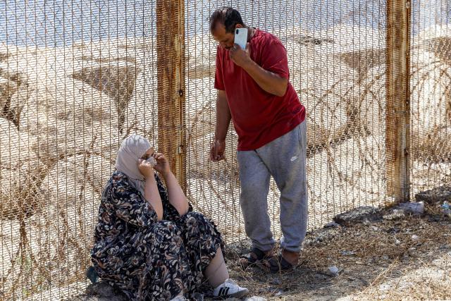 Relatives and friends wait by a fence topped with barbed-wire for the return of people who had previously crossed into Spain's North African enclave of Ceuta, at Morocca's Bab Sebta border crossing on the outskirts of Fnideq on August 2, 2026. As many as 60,000 migrants entered Ceuta in recent days, mostly swimming around the small border post that juts into the Mediterranean Sea, in an unprecedented surge that prompted an international crisis for Spain. The mass crossing into the tiny Spanish territory resulted in at least 67 deaths, according to Spanish authorities, and led to clashes with Moroccan police on the shared border. (Photo by Abdel Majid BZIOUAT / AFP)