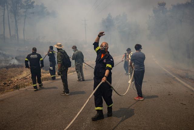 TOPSHOT - Volunteers and Greek firefighters work to extinguish a wildfire near Porto Germeno, some 70 kilometres (45 miles) northwest of Athens in the region of Viotia, on August 2, 2026. Greece on August 2, 2026, faced multiple fronts and a growing damage toll after a week of wildfires devastated over 12,000 hectares of forest and agricultural land, experts said. Porto Germeno and other villages were evacuated when the fire broke out on July 31, but local authorities say scores of homes were damaged or destroyed. Hit hard by the climate crisis like the rest of the Mediterranean region, the country is plagued by wildfires every summer due to high temperatures, frequent heat waves, and drought. (Photo by Angelos TZORTZINIS / AFP)