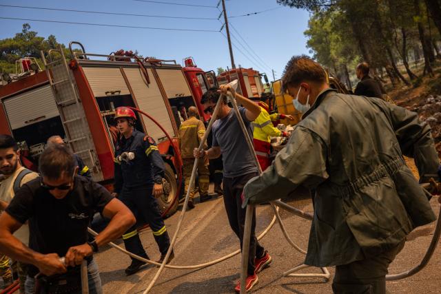 Volunteers and Greek firefighters work to extinguish a wildfire near Porto Germeno, some 70 kilometres (45 miles) northwest of Athens in the region of Viotia, on August 2, 2026. Greece on August 2, 2026, faced multiple fronts and a growing damage toll after a week of wildfires devastated over 12,000 hectares of forest and agricultural land, experts said. Porto Germeno and other villages were evacuated when the fire broke out on July 31, but local authorities say scores of homes were damaged or destroyed. Hit hard by the climate crisis like the rest of the Mediterranean region, the country is plagued by wildfires every summer due to high temperatures, frequent heat waves, and drought. (Photo by Angelos TZORTZINIS / AFP)