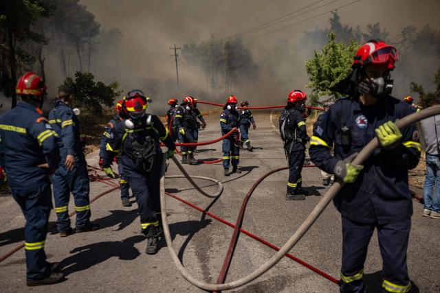 Greek firefighter hold hoses during operations against a wildfire in the area of Porto Germeno, some 70 kilometres (45 miles) northwest of Athens in the region of Viotia, on August 2, 2026. Greece on August 2, 2026, faced multiple fronts and a growing damage toll after a week of wildfires devastated over 12,000 hectares of forest and agricultural land, experts said. Porto Germeno and other villages were evacuated when the fire broke out on July 31, but local authorities say scores of homes were damaged or destroyed. Hit hard by the climate crisis like the rest of the Mediterranean region, the country is plagued by wildfires every summer due to high temperatures, frequent heat waves, and drought. (Photo by Angelos TZORTZINIS / AFP)