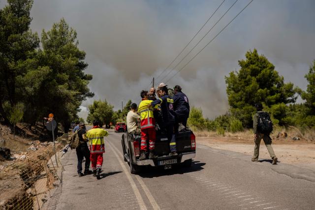 Volunteers and firefighters head towards a wildfire for extinguishing operations in the Porto Germeno area, some 70 kilometres (45 miles) northwest of Athens, in the region of Viotia, on August 2, 2026. Greece on August 2, 2026, faced multiple fronts and a growing damage toll after a week of wildfires devastated over 12,000 hectares of forest and agricultural land, experts said. Porto Germeno and other villages were evacuated when the fire broke out on July 31, but local authorities say scores of homes were damaged or destroyed. Hit hard by the climate crisis like the rest of the Mediterranean region, the country is plagued by wildfires every summer due to high temperatures, frequent heat waves, and drought. (Photo by Angelos TZORTZINIS / AFP)