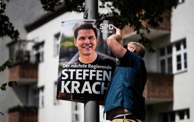 An activist of the Social Democratic Party (SPD) puts up an election poster featuring a portrait of the SPD's main candidate in upcoming regional elections in Berlin Steffen Krach on August 2, 2026. Berlin goes to the polls on September 20, 2026. (Photo by John MACDOUGALL / AFP)
