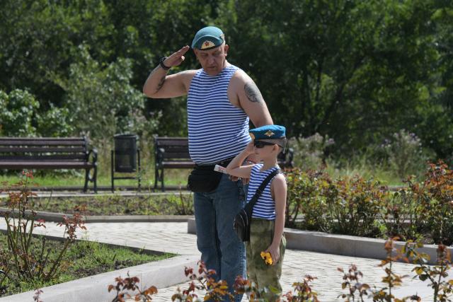 A military veteran and a child salute at the monument to Vasily Margelov, Commander of the Soviet Airborne Forces, during Paratroopers' Day celebrations in Donetsk, Russian-controlled Ukraine on August 2, 2026, amid the ongoing Russian-Ukrainian conflict. (Photo by AFP)