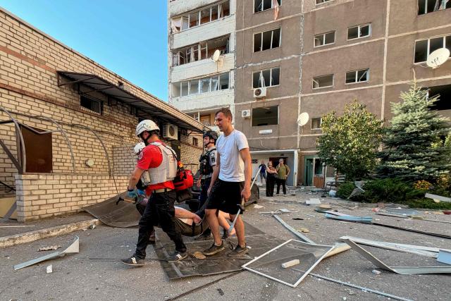 An injured person is evacuated in front of a damaged residential building at the site of a Russian airstrike in Zaporizhzhia on August 2, 2026, amid the Russian invasion of Ukraine. (Photo by Darya NAZAROVA / AFP)