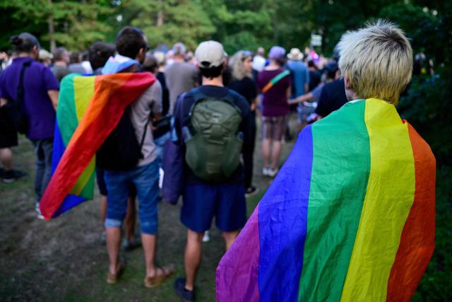 People, some drapped in rainbow flags, pay their respects at a makeshift memorial in tribute to the victims at the Tiergarten park in Berlin on August 2, 2026, a week after a car ramming attack that killed one person and injured 29 near the Christopher Street Day (CSD) parade. Placard which reads "Equal Solidarity for all those affected". German police had shot and killed the chief suspect in what officials described as a deadly Islamist attack near the Berlin Pride parade the night prior, the latest ramming assault to hit the country. The attack late on July 25 -- the first such incident to target the German capital's LGBTQ community, killed one woman and wounded 29 others. (Photo by John MACDOUGALL / AFP)