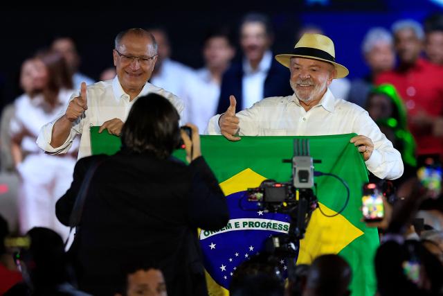 Brazil's Vice-President Geraldo Alckmin (L) and Brazil's President Luiz Inacio Lula da Silva hold a Brazilian flag and gesture from a stage during the Workers' Party (PT) national convention in Sao Paulo, Brazil, on August 2, 2026, where Lula formally announces his bid for re-election. At 80, President Lula on July 2 launches his bid for re-election, casting himself as a defender of Brazil's "sovereignty" as pressure from President Donald Trump's administration casts a shadow over the campaign. (Photo by Miguel SCHINCARIOL / AFP)