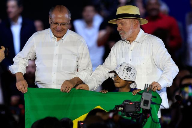 Brazil's President Luiz Inacio Lula da Silva (L) and Brazil's Vice-President Geraldo Alckmin hold a Brazilian flag during the Workers' Party (PT) national convention in Sao Paulo, Brazil, on August 2, 2026, where Lula formally announced his bid for re-election. At 80, President Lula on July 2 launches his bid for re-election, casting himself as a defender of Brazil's "sovereignty" as pressure from President Donald Trump's administration casts a shadow over the campaign. (Photo by Miguel SCHINCARIOL / AFP)