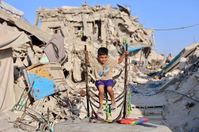 A Palestinian child plays amongst the rubble of a destroyed building in the Jabalia camp for Palestinian refugees in the northern Gaza Strip on August 2, 2026. Israeli strikes on Gaza hit multiple residential buildings and killed at least 13 people, authorities said on August 2, despite Hamas saying it agreed to the latest stage of a deal to end the war. Hamas said on July 31 it had agreed to a plan championed by US President Donald Trump that includes provisions for handing over its weapons and the gradual withdrawal of Israeli forces from the Gaza Strip. (Photo by Omar AL-QATTAA / AFP)