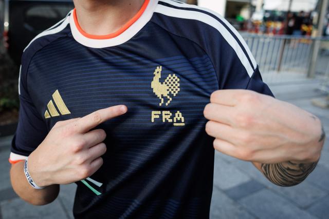 A member of the French national e-sports team shows the jersey's team logo at an event for the Esports World Cup on the Champs Elysee avenue on August 2, 2026. (Photo by Simon WOHLFAHRT / AFP)