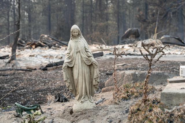 A Virgin Mary statue remains untouched in front of a burned out residential home in the Balboa neighborhood of Spokane, Washington, on August 2, 2026. Fast-moving fires left a trail of destruction in the northwestern US city of Spokane on Sunday, with officials reporting hundreds of structures reduced to cinders.
Thousands of people were ordered to evacuate their homes Saturday and overnight into Sunday, as three separate fires broke out in and around the city in the east of Washington state. (Photo by Erick Doxey / AFP) / ALTERNATIVE CROP