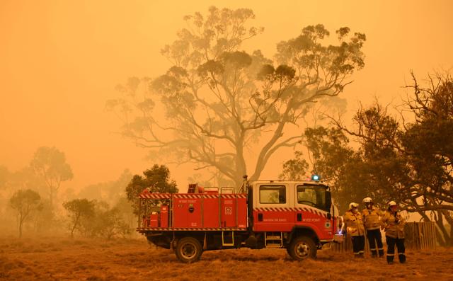 (FILES) Firefighters protect a property from bushfires burning near the town of Bumbalong south of Canberra on February 1, 2020. Europe has suffered some of its worst wildfires in living memory, extreme weather events scientists have linked to human-made climate change. For Australians it's all too familiar. (Photo by PETER PARKS / AFP)