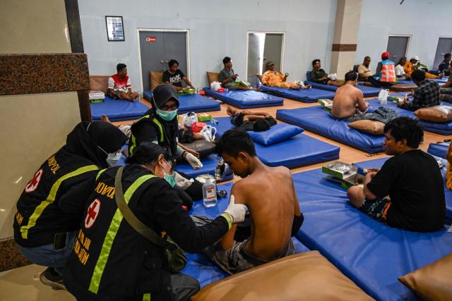 A survivor of a ferry fire is given medical attention at Tanjung Perak port in Surabaya on August 3, 2026, a day after the disaster that killed at least five people and prompted many to jump from the vessel into the sea. Survivors spoke August 3 of multiple blasts moments before an Indonesian passenger ferry caught fire, killing five passengers and prompting many to jump into the sea -- several still missing more than 24 hours later. (Photo by JUNI KRISWANTO / AFP)