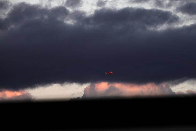 A Qantas plane flies before cumulonimbus clouds at sunset above Sydney on August 3, 2026. (Photo by SAEED KHAN / AFP)