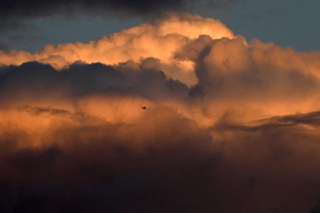A Qantas plane flies before cumulonimbus clouds at sunset above Sydney on August 3, 2026. (Photo by SAEED KHAN / AFP)