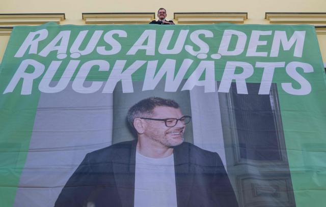 The Green Party's main candidate in upcoming regional elections in Berlin Werner Graf poses next to a giant election campaign banner hanging on the facade of the Green Party's federal headquarters in Berlin on August 3, 2026. Berlin goes to the polls on September 20, 2026. (Photo by John MACDOUGALL / AFP)