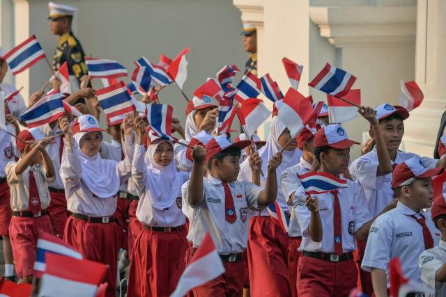 Students wave the national flags of Indonesia and Thailand before a welcome ceremony for Thailand’s Prime Minister Anutin Charnvirakul at Merdeka Palace in Jakarta on August 3, 2026. (Photo by BAY ISMOYO / AFP)