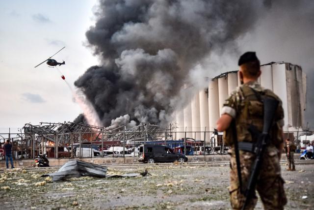EDITORS NOTE: Graphic content / (FILES) Lebanese army soldiers stand while behind a helicopter puts out a fire at the scene of an explosion at the port of Lebanon's capital Beirut on August 4, 2020. Lebanese President Joseph Aoun on August 3, 2026 urged the judiciary to issue a long-awaited indictment over the 2020 Beirut port blast, on the eve of the catastrophe's sixth anniversary. (Photo by AFP)