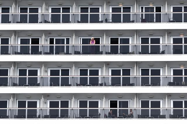 TOPSHOT - A cruise passenger looks on from a cabin balcony aboard an MSC Cruises ship docked at the Grand Port Maritime de Marseillein Marseille, southeastern France, on July 31, 2026. (Photo by Thibaud MORITZ / AFP)