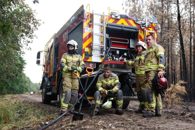 Ukrainian firefighters aiding in the fight against France's ongoing wildfires rest near their vehicle as they work to put out smouldering vegetation near the village of Le Temple, southwestern France, on August 3, 2026. A massive fire in the near the Arcachon Bay in the Gironde department started on July 22, forcing 220 people to flee their homes to safety. The fire went on to incinerate some 42,000 hectares (104,000 acres) of pine forest along the Atlantic coastline, destroying some 240 homes in its wake. (Photo by ROMAIN PERROCHEAU / AFP)