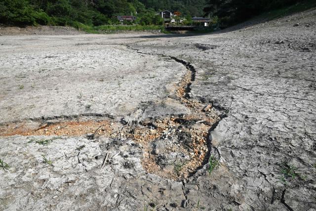 A general view shows the dried up bed of a reservoir in Miryang on August 3, 2026, as a scorching heat wave continues to grip South Korea. South Korea's weather agency issued a "severe heatwave warning" for Seoul on August 3, the first such advisory since introducing the designation this year to alert the public about extreme temperatures. (Photo by Jung Yeon-je / AFP)