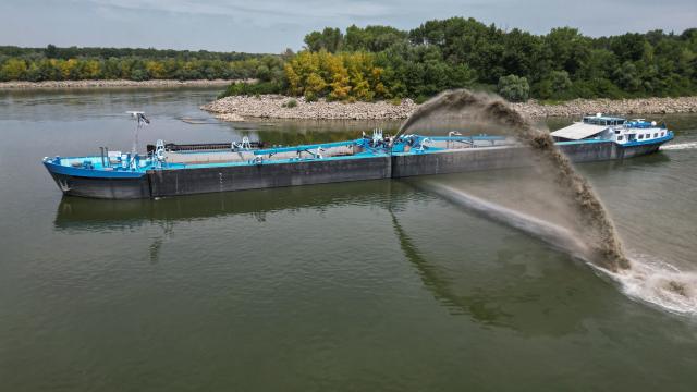 An aerial view shows a dredge ship at the splitting point of Danube with Bala branch and Old Danube, the place where a controlled underwater explosion took place on the riverbed of the Danube River in Izvoarele village, on August 3, 2026. The blast aimed at deepening the channel and diverting a higher volume of water toward the cooling systems of the Cernavoda Nuclear Power Plant. Local authorities and plant engineers authorized the blasting operations to counteract critically low water levels caused by a prolonged summer heatwave, ensuring the continuous and safe operation of the facility's reactors. (Photo by Daniel MIHAILESCU / AFP)