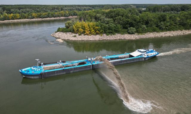 An aerial view shows a dredge ship at the splitting point of Danube with Bala branch and Old Danube, the place where a controlled underwater explosion took place on the riverbed of the Danube River in Izvoarele village, on August 3, 2026. The blast aimed at deepening the channel and diverting a higher volume of water toward the cooling systems of the Cernavoda Nuclear Power Plant. Local authorities and plant engineers authorized the blasting operations to counteract critically low water levels caused by a prolonged summer heatwave, ensuring the continuous and safe operation of the facility's reactors. (Photo by Daniel MIHAILESCU / AFP)