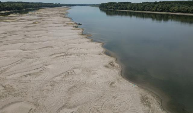 An aerial view shows a dried-out river bed of Danube in Rasova village August 3, 2026. Romanian army forces detonated an explosive load into the rock bed of Danube in Izvoarele village, kilometers away from Rasova, to help diverting a higher volume of water toward the cooling systems of the Cernavoda Nuclear Power Plant. Local authorities and plant engineers authorized the blasting operations to counteract critically low water levels caused by a prolonged summer heatwave, ensuring the continuous and safe operation of the facility's reactors. (Photo by Daniel MIHAILESCU / AFP)