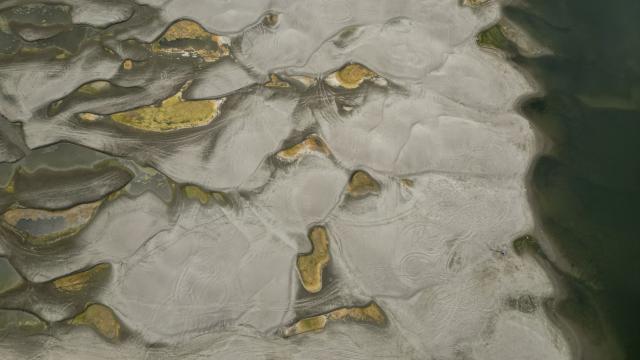 An aerial view shows a dried-out river bed of Danube in Rasova village August 3, 2026. Romanian army forces detonated an explosive load into the rock bed of Danube in Izvoarele village, kilometers away from Rasova, to help diverting a higher volume of water toward the cooling systems of the Cernavoda Nuclear Power Plant. Local authorities and plant engineers authorized the blasting operations to counteract critically low water levels caused by a prolonged summer heatwave, ensuring the continuous and safe operation of the facility's reactors. (Photo by Daniel MIHAILESCU / AFP)