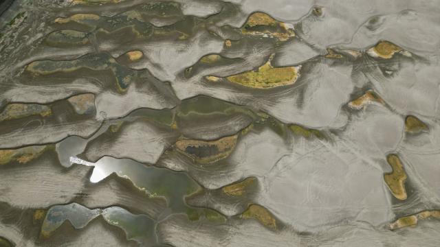 An aerial view shows a dried-out river bed of Danube in Rasova village August 3, 2026. Romanian army forces detonated an explosive load into the rock bed of Danube in Izvoarele village, kilometers away from Rasova, to help diverting a higher volume of water toward the cooling systems of the Cernavoda Nuclear Power Plant. Local authorities and plant engineers authorized the blasting operations to counteract critically low water levels caused by a prolonged summer heatwave, ensuring the continuous and safe operation of the facility's reactors. (Photo by Daniel MIHAILESCU / AFP)