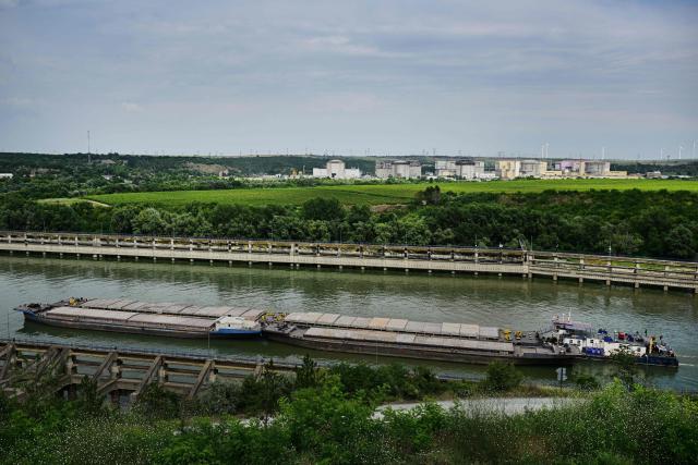 The Cernavoda nuclear plant in Cernavoda city is seen in the background as a barge on the Danube-Black Sea navigation channel in Cernavoda city on August 3, 2026. Romanian army forces detonate an explosive load into the rock bed of Danube in Izvoarele village - upstream from Cernavoda- to help diverting a higher volume of water toward the cooling systems of the Cernavod? Nuclear Power Plant. Local authorities and plant engineers authorized the blasting operations to counteract critically low water levels caused by a prolonged summer heatwave, ensuring the continuous and safe operation of the facility's reactors. (Photo by Daniel MIHAILESCU / AFP)