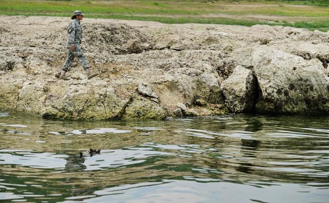 A Romanian army personnel inspects the bedrock of shallow waters of Danube after a controlled explosion next Izvoarele village August 3, 2026. Romanian army forces detonated an explosive load into the rock bed of Danube in Izvoarele village to help diverting a higher volume of water toward the cooling systems of the Cernavoda Nuclear Power Plant. Local authorities and plant engineers authorized the blasting operations to counteract critically low water levels caused by a prolonged summer heatwave, ensuring the continuous and safe operation of the facility's reactors. (Photo by Daniel MIHAILESCU / AFP)
