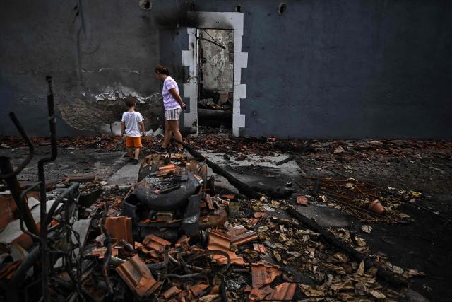 Residents walk past the entrance to their completely burnt-out house in Le Porge, southwestern France, on August 3, 2026, after authorities allowed residents to return to their homes. (Photo by Christophe ARCHAMBAULT / AFP)