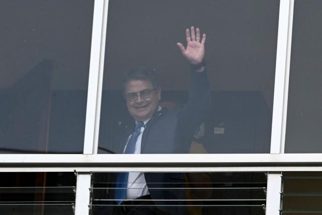 Former Honduras' President (2014-2022) Juan Orlando Hernandez waves as he arrives for a hearing at the Supreme Court of Justice in Tegucigalpa on August 3, 2026. Hernandez is accused of fraud and money-laundering charges, which he denies, claiming to be the continued victim of "persecution." A judge suspended an arrest warrant against him, as he agreed to appear voluntarily after US President Donald Trump pardoned him a 45-year prison sentence last year. (Photo by Orlando SIERRA / AFP)