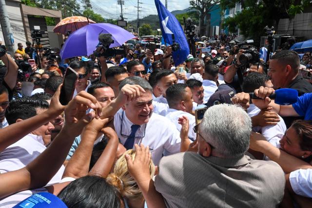 Former Honduras' President (2014-2022) Juan Orlando Hernandez greets supporters following a hearing at the Supreme Court of Justice in Tegucigalpa on August 3, 2026. Hernandez is accused of fraud and money-laundering charges, which he denies, claiming to be the continued victim of "persecution." A judge suspended an arrest warrant against him, as he agreed to appear voluntarily after US President Donald Trump pardoned him a 45-year prison sentence last year. (Photo by Orlando SIERRA / AFP)