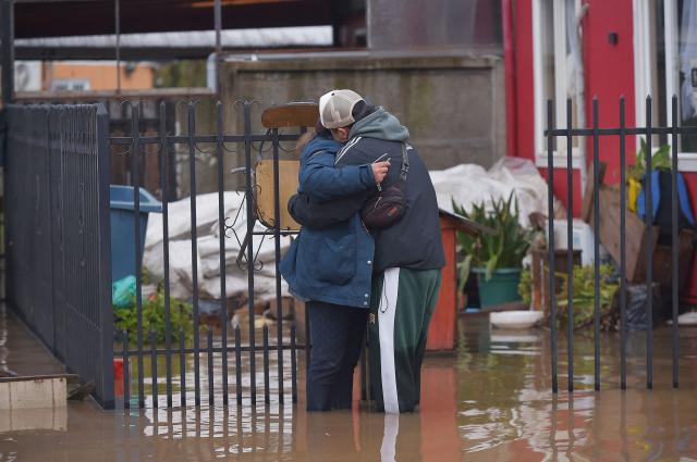 A man and a woman embrace in a flooded area of Angol, Araucania region, southern Chile, on August 3, 2026, following heavy rains. (Photo by GUILLERMO SALGADO / AFP)