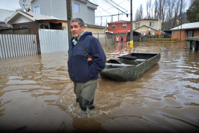 A man wades beside his boat in a flooded area of Angol, Araucania region, southern Chile, on August 3, 2026, following heavy rains that affected the area. (Photo by GUILLERMO SALGADO / AFP)
