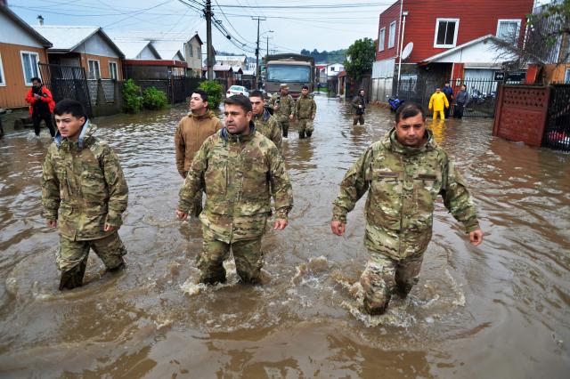 Chilean soldiers wade as they patrol a flooded area of Angol, Araucania region, southern Chile, on August 3, 2026, following heavy rains. (Photo by GUILLERMO SALGADO / AFP)