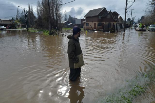 A man stands on a flooded street of Angol, Araucania region, southern Chile, on August 3, 2026, following heavy rains. (Photo by GUILLERMO SALGADO / AFP)